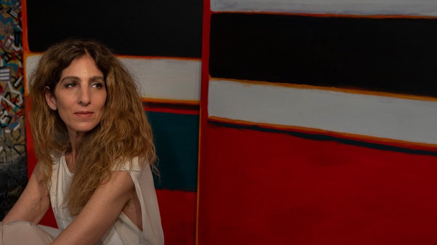 Paola Lettieri seated in front of her paintings.